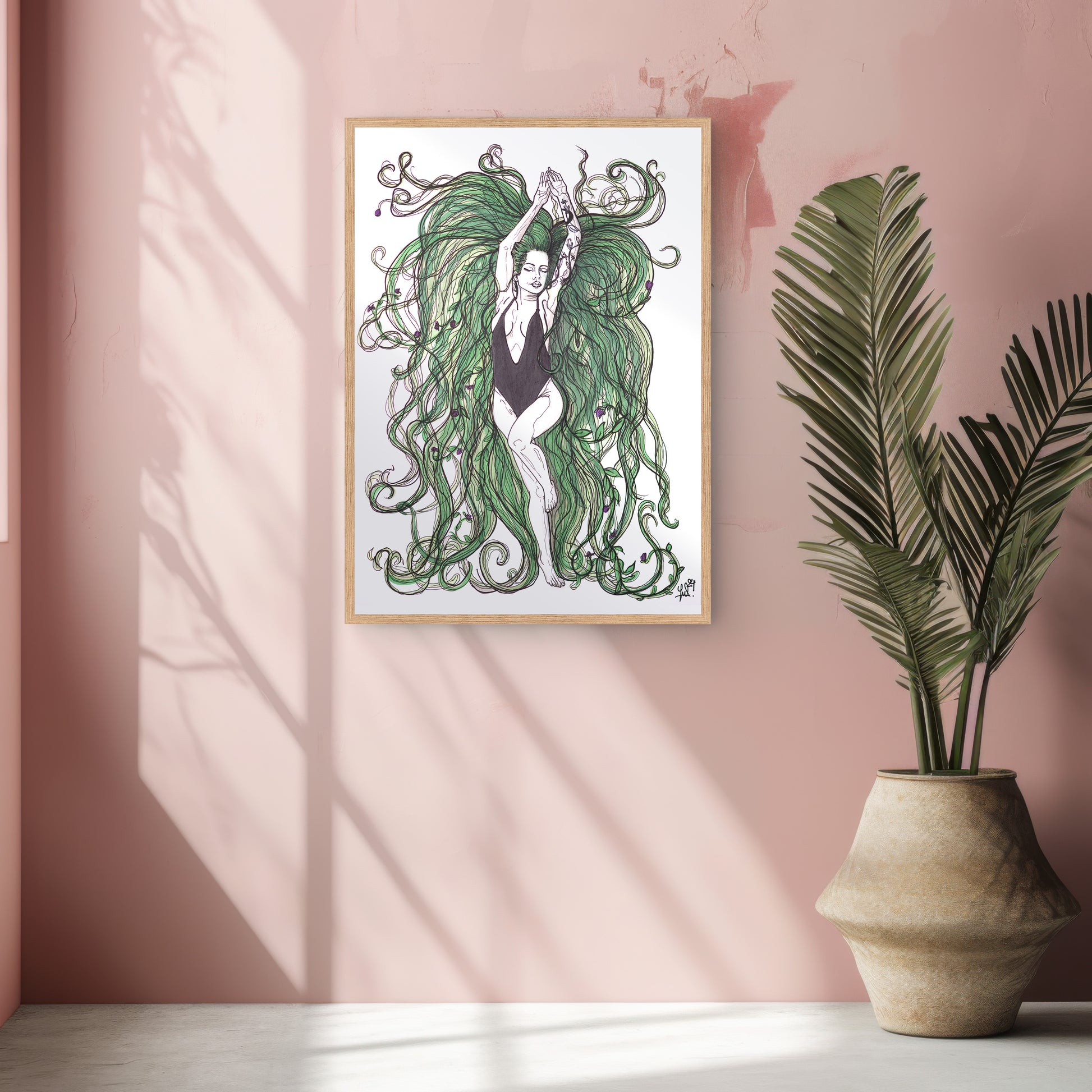 Framed artwork of a woman with green hair on a pink wall next to a potted plant. A piece on our relationship with our Mother Earth.